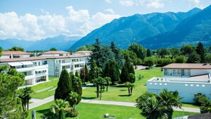 A residential area with modern buildings, green lawns, and mountains in the background. - Villa Delta – Parkhotel Delta (Ascona)