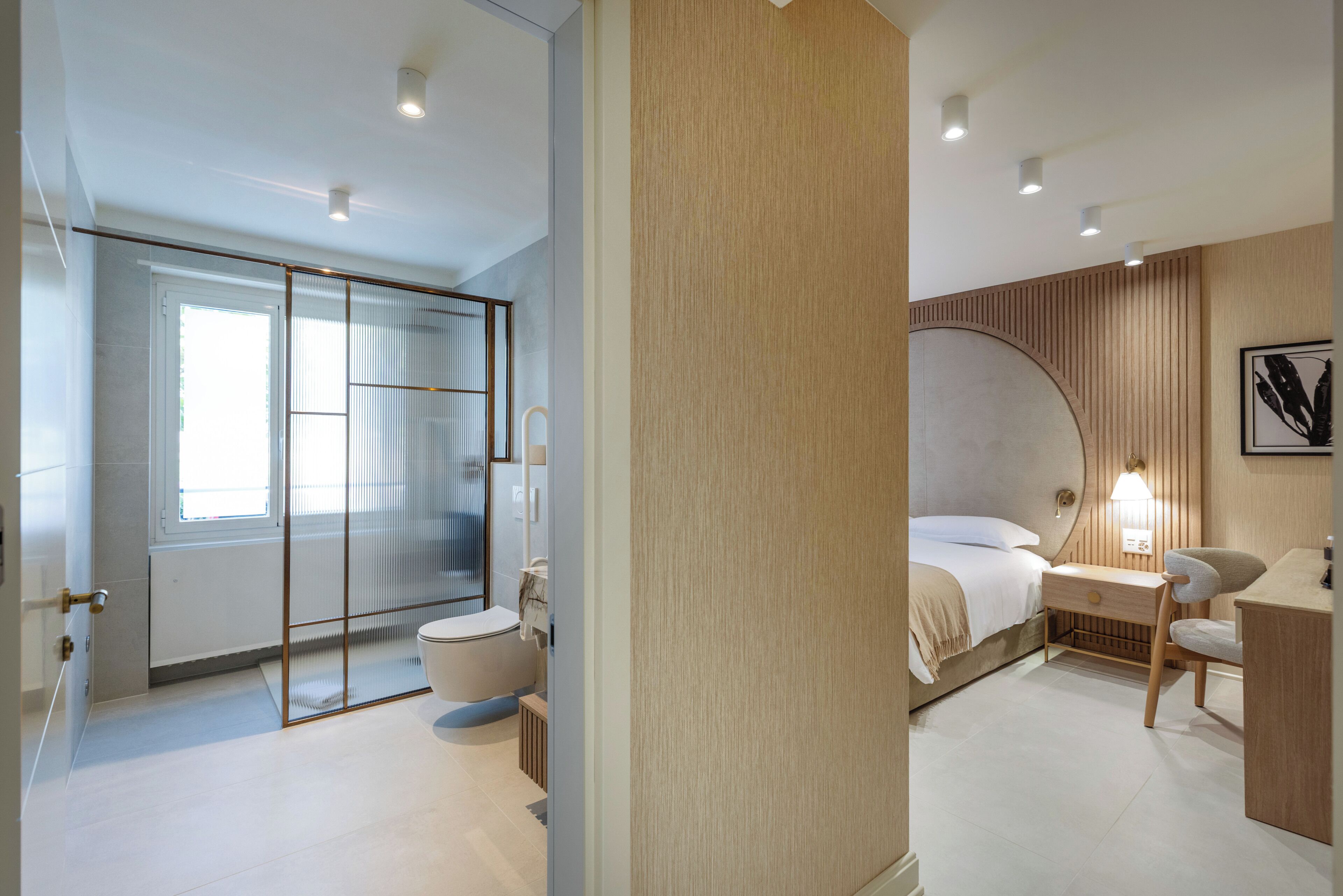 A modern bedroom with a large bed, a bedside table, a chair, and a walk-in closet with sliding doors.