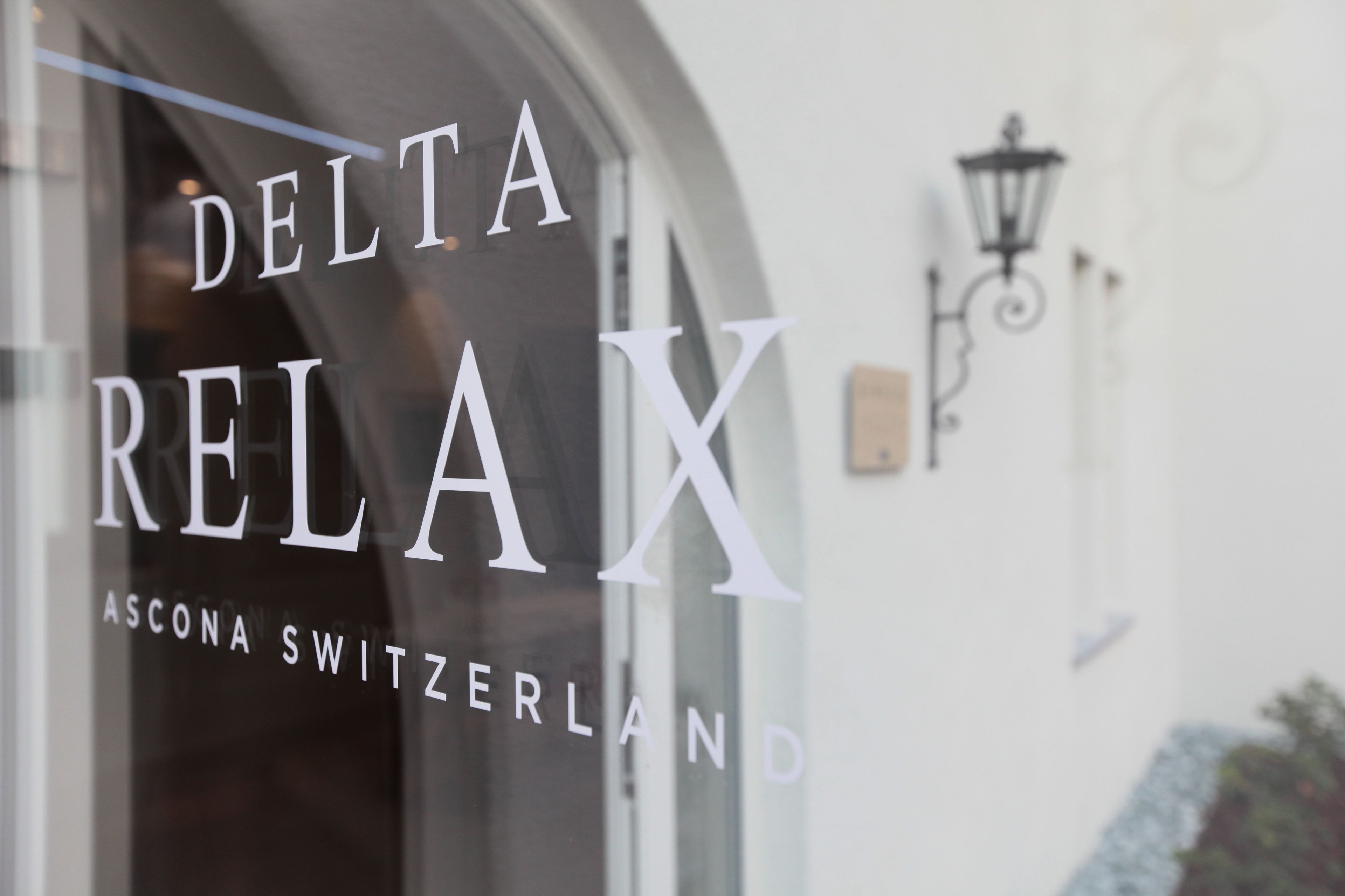 Une enseigne indiquant « Delta Relax Ascona Suisse », avec un lampadaire en arrière-plan.