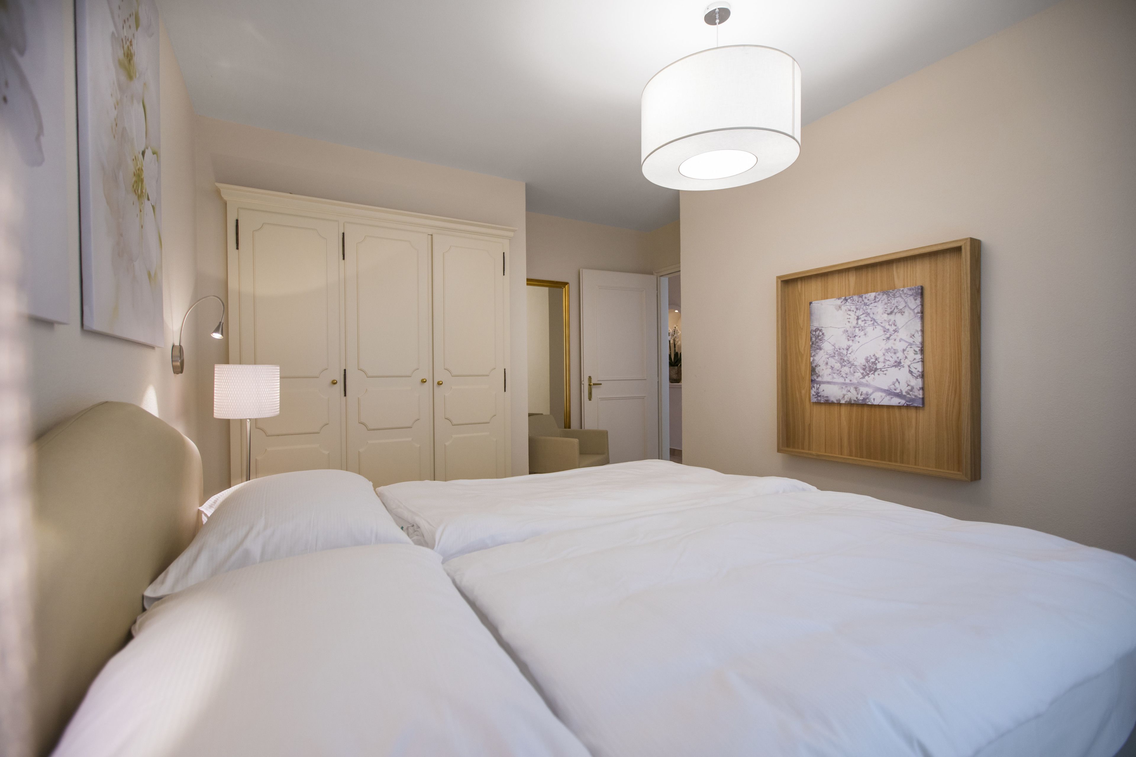 Hotellihuone, jossa on suuri sänky, työpöytä, tuoli, vaatekaappi ja taulu seinällä.