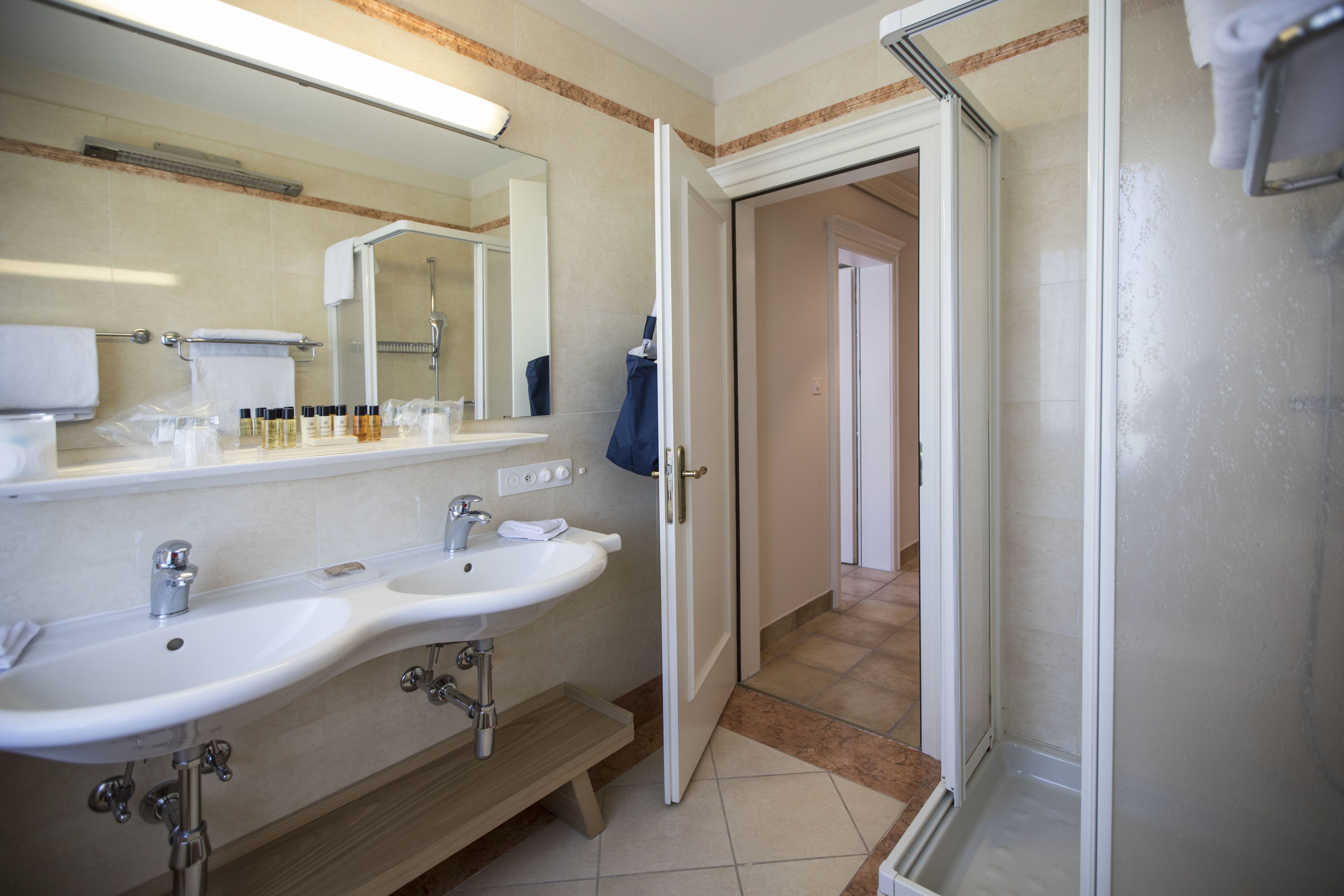 Un baño con dos lavamanos, un espejo y una zona de ducha.