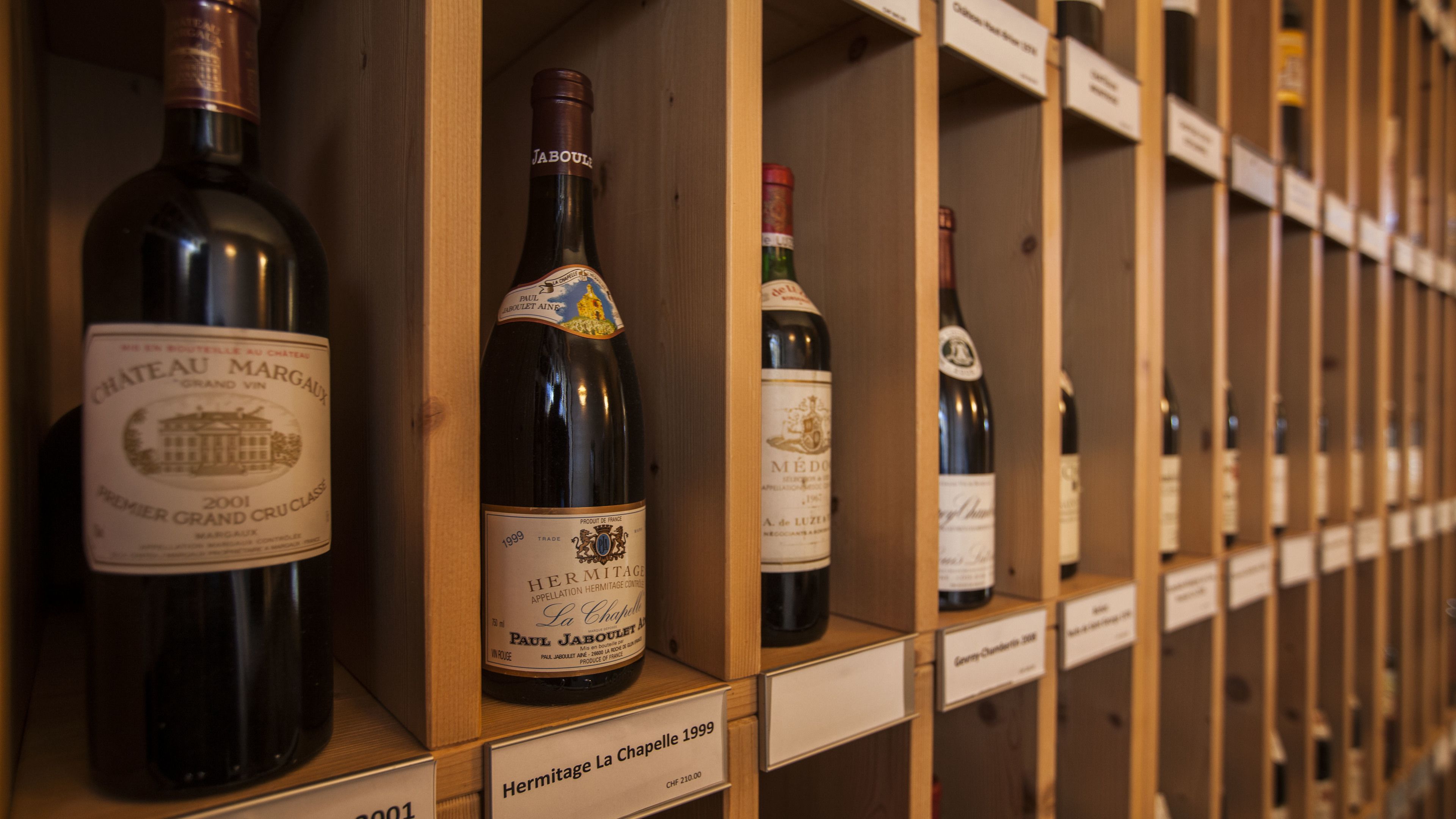A wine rack with bottles labeled with names and years.