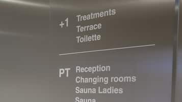 A sign listing hotel amenities including treatments, reception, changing rooms, saunas, fitness, relax areas, showers, and toilets.