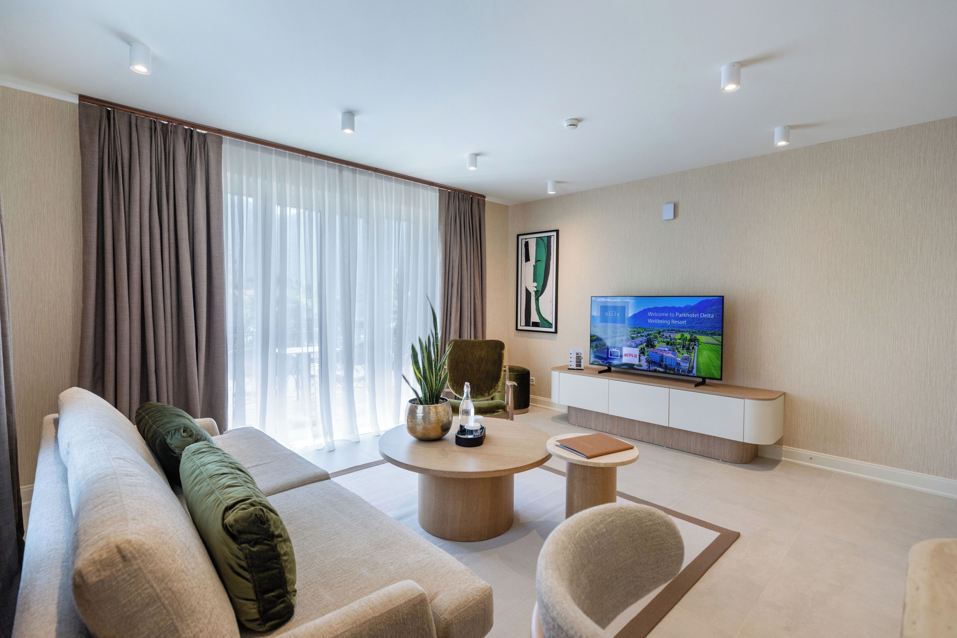 Una sala de estar moderna con un sofá, una mesa de centro, un televisor y una planta en maceta.