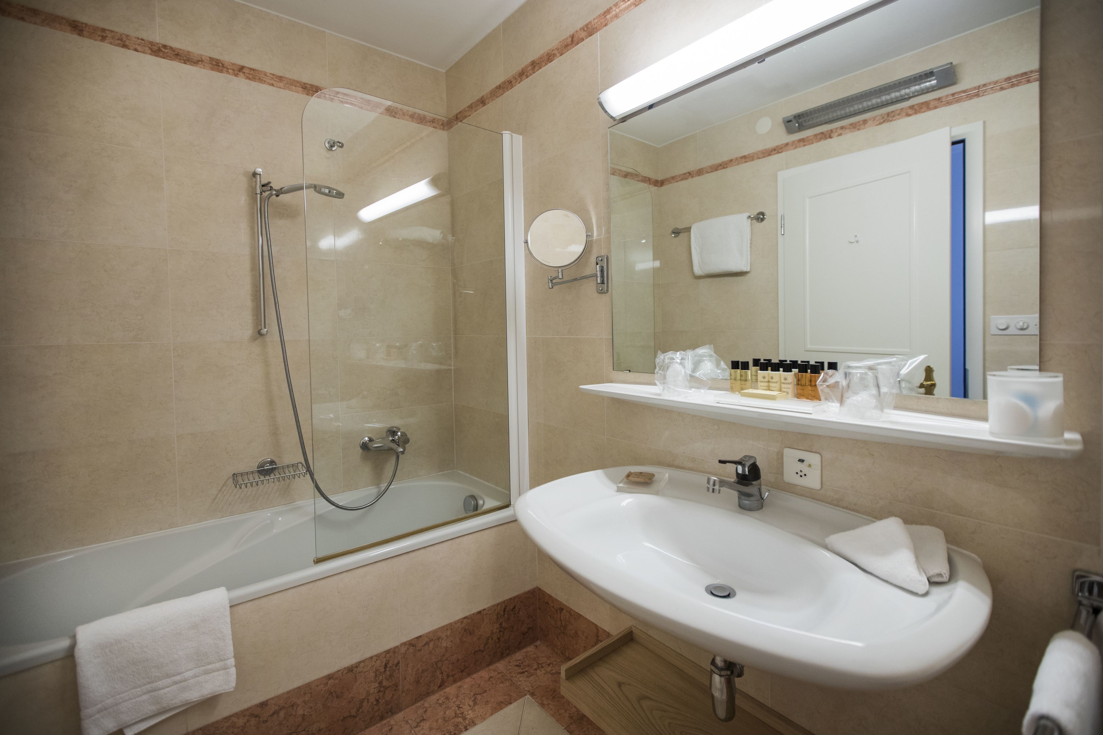 Un bagno moderno con doccia vetrata, lavandino bianco e specchio sopra al lavandino.