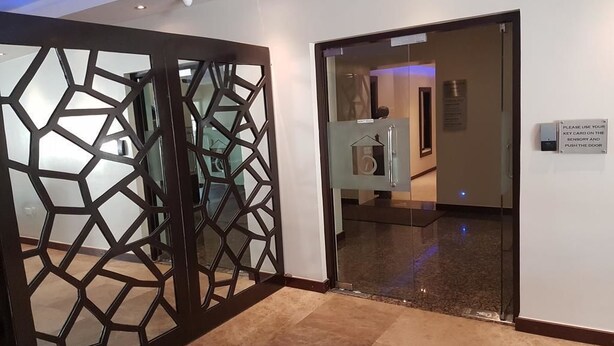A hotel lobby with a geometric decorative partition, a reception desk, and a sign instructing to use a key card on the security and public door. - Check Inn Hotel Abuja (Abuja)