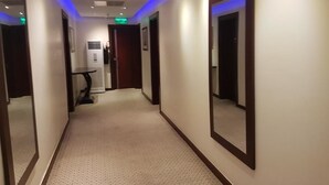A hotel hallway with mirrored walls, a carpeted floor, and recessed lighting. - Check Inn Hotel Abuja (Abuja)