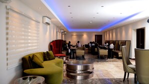 A hotel lobby with seating areas, a reception desk, and a large window with blinds. - Check Inn Hotel Abuja (Abuja)