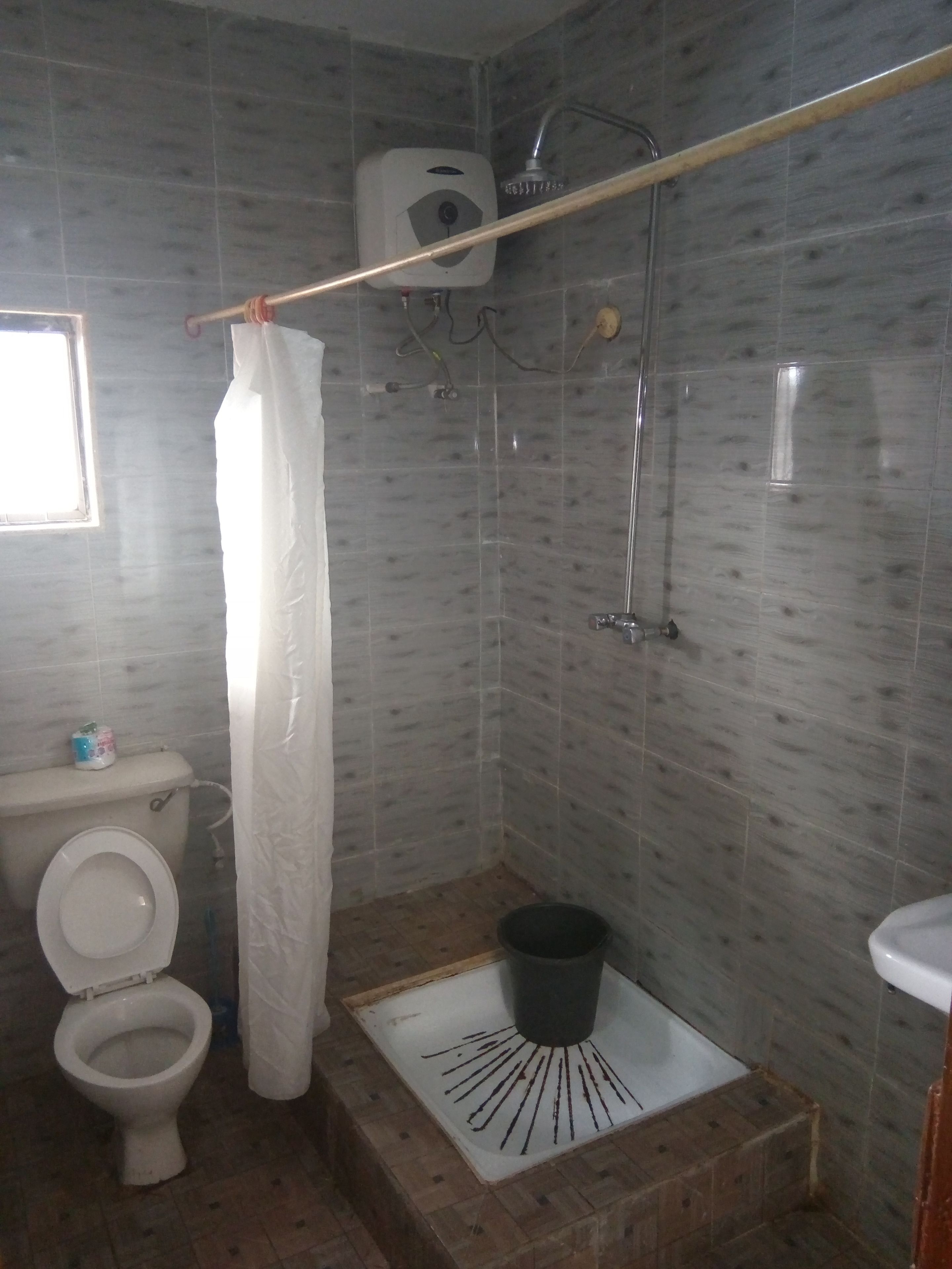 A bathroom with a shower, toilet, and a small sink.