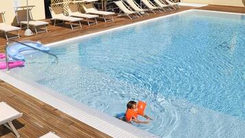 Ein Schwimmbad mit Liegestühlen und einem Whirlpool-Bereich.