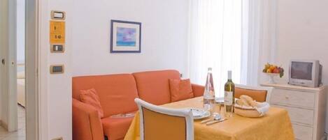 Un soggiorno compatto con divano, tavolo da pranzo e televisione.
