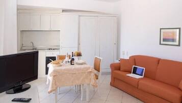 Un espace de vie compact comprenant un coin repas, une kitchenette et un canapé avec un ordinateur portable.