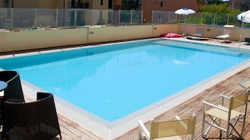 Una piscina al aire libre de temporada, sillones reclinables de piscina