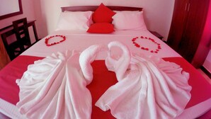 A neatly made bed with red pillows and a red and white blanket. There are two white towels arranged on the bed. - Colombo Residency (Colombo)