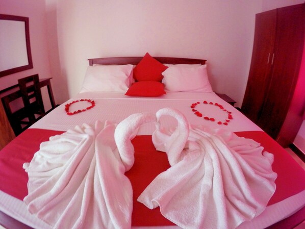 A neatly made bed with red pillows and a red and white blanket. There are two white towels arranged on the bed. - Colombo Residency (Colombo)