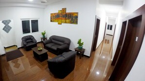 Una sala de estar con un sofá, dos sillones, una mesa de centro y un cuadro en la pared.