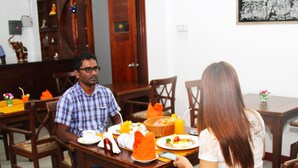 A dining area with wooden furniture, a dining table set with plates, glasses, and a basket. - Colombo Residency (Colombo)
