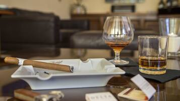 A cigar on a tray, a glass of whiskey, and a glass of water on a table.