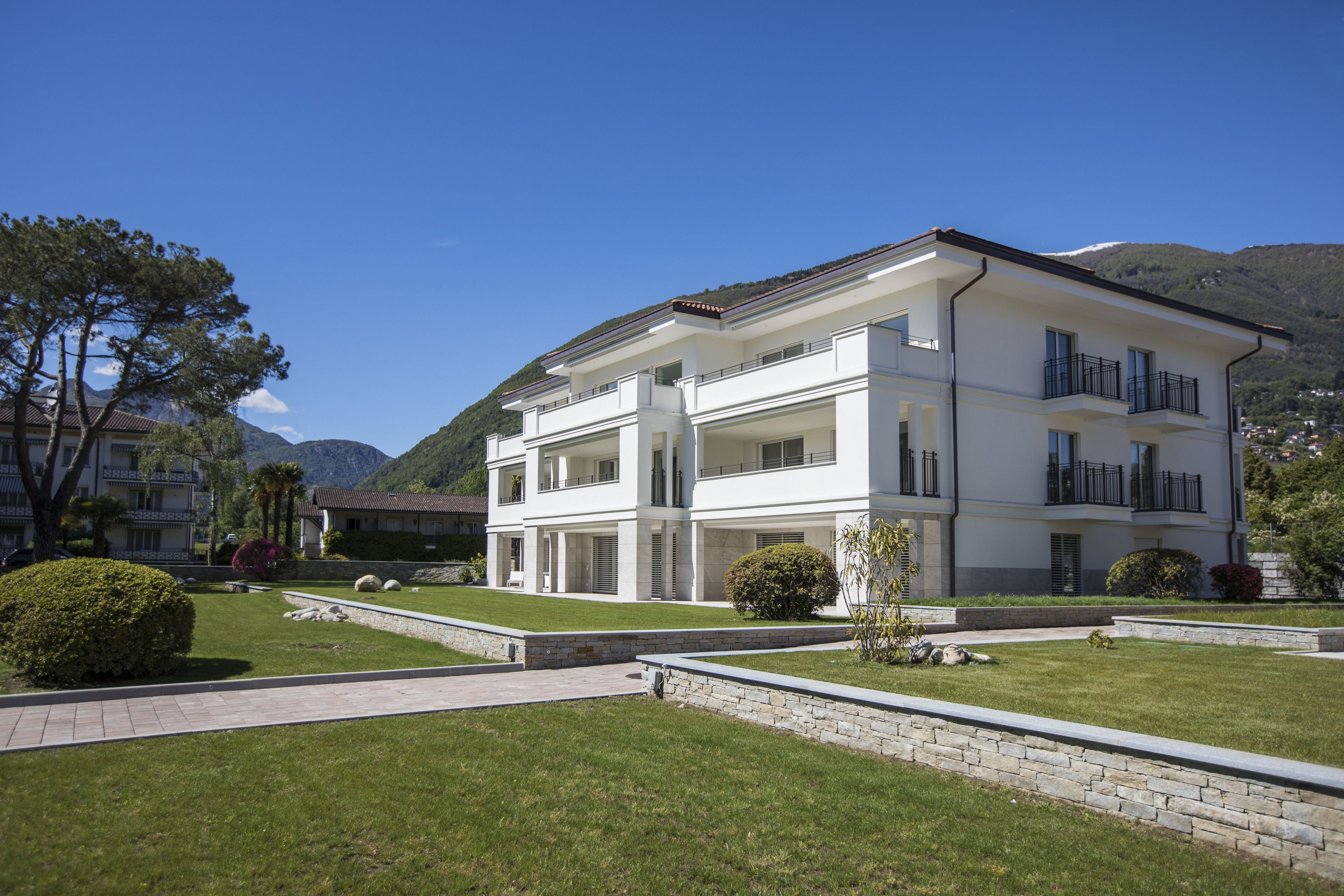 A modern two-story building with a flat roof, large windows, and a balcony on the upper floor.