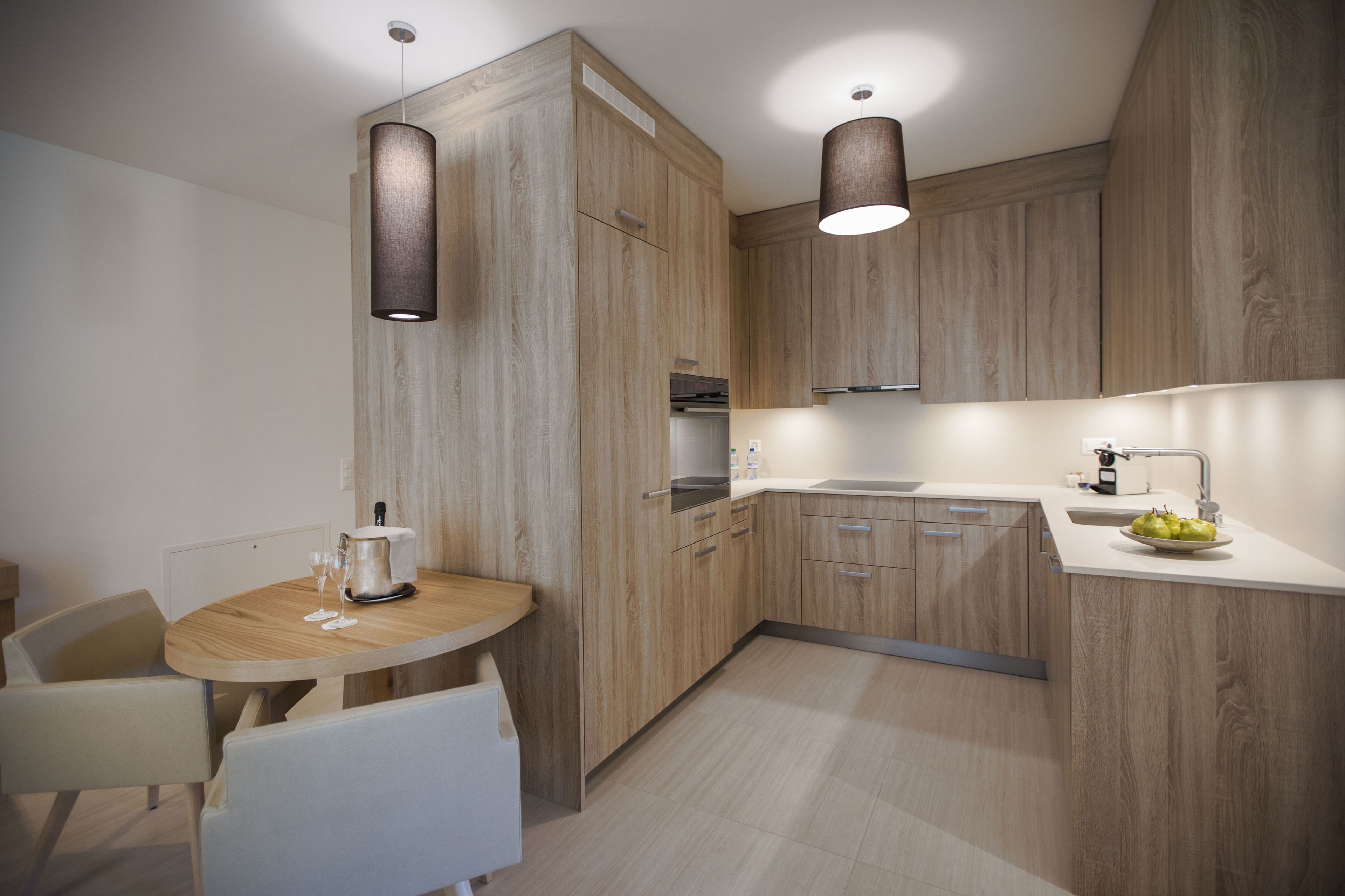 Una cucina moderna con mobili in legno, un tavolo rotondo e lampade a sospensione.