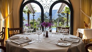 A table set for two with a view of mountains and a pool. - Delta Resort Apartments (Ascona)