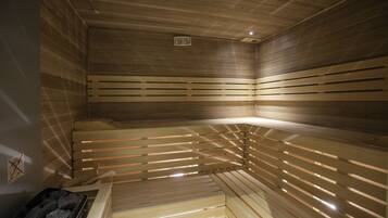 Un sauna avec des bancs en bois et un banc sur lequel se trouve un plateau rempli de pierres.
