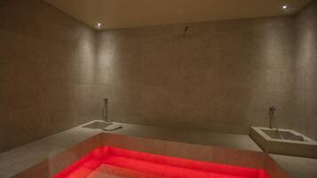Une salle de bain moderne dotée d’un grand jacuzzi rectangulaire, de deux espaces douche séparés et d’un sol carrelé.