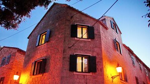 A stone building with multiple windows, some with shutters, and exterior lighting fixtures. - Villa Desideria (Split)