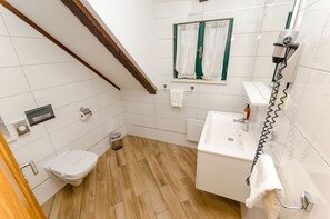 A small bathroom with a toilet, sink, and a hairdryer on a wall-mounted rack. - Villa Desideria (Split)