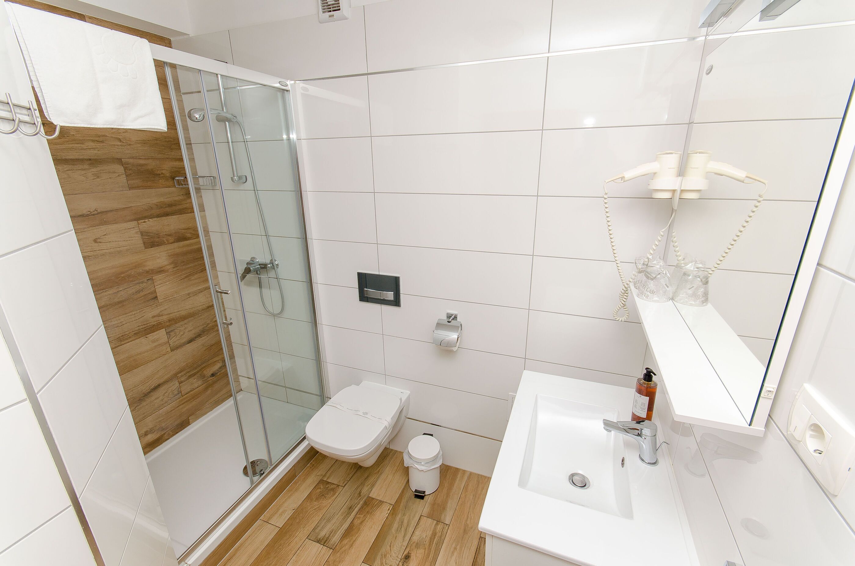 Un baño moderno con ducha acristalada, inodoro y lavamanos.