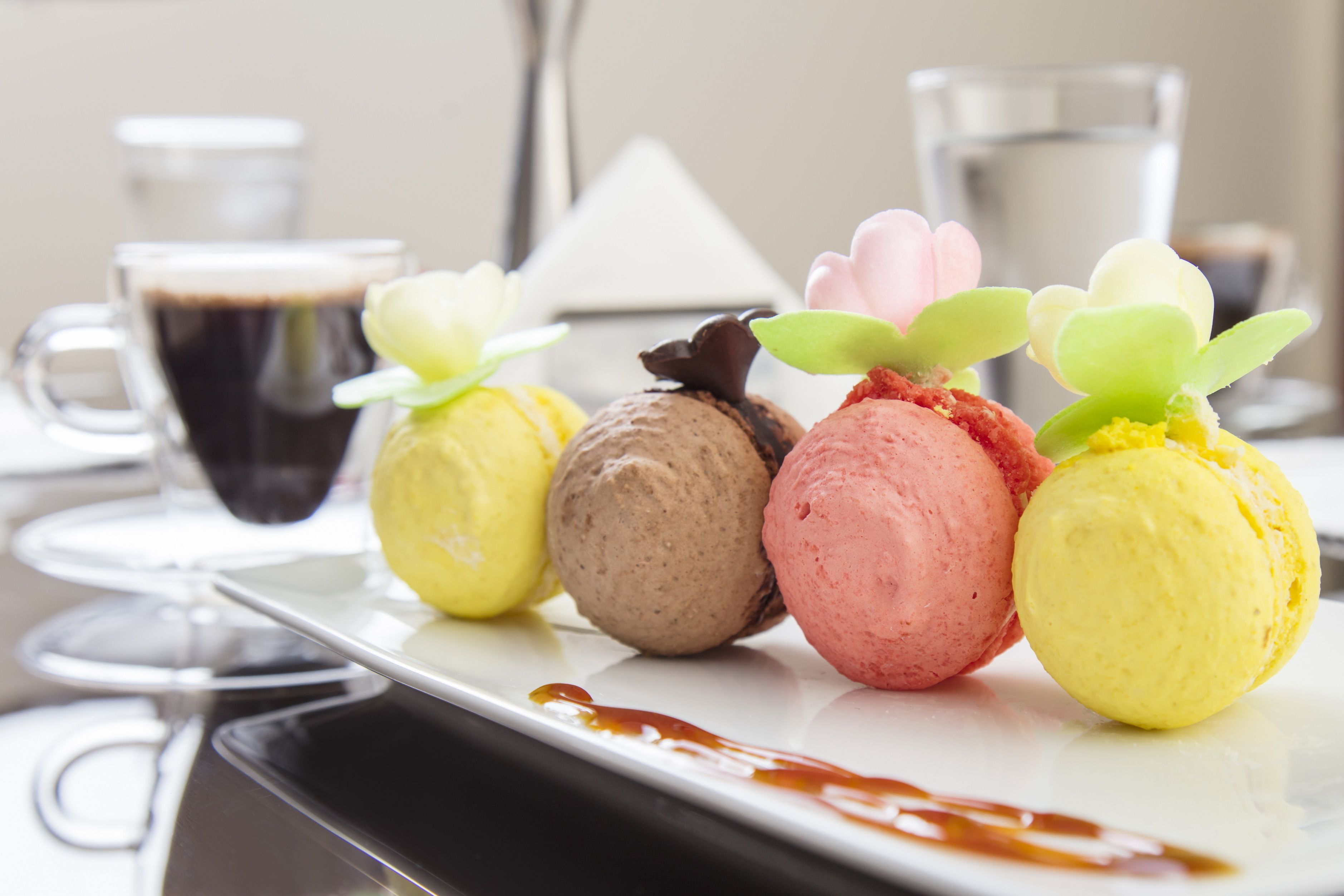 Un plato de postre con cuatro bolas de helado y una pequeña decoración floral.