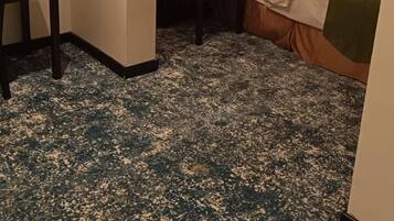 A hotel room with a bed, bedside tables, a desk, and a carpeted floor.