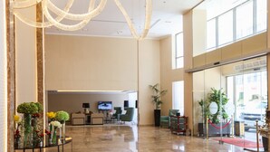 Een ruime lobby met een moderne kroonluchter, zitgedeelte en een receptiebalie.