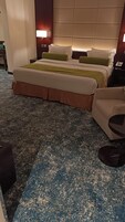 Habitación de hotel con una cama grande, un sofá, una mesita y piso alfombrado.