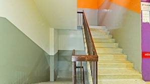 Eine Treppe mit Metallgeländer, Fliesenboden und einer Wand mit einem Schild, das die dritte Etage anzeigt.