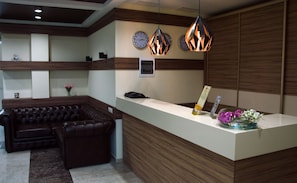 Relax in comfort on the sleek sofa, surrounded by a modern reception area with a convenient desk and time-telling clocks.