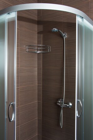 Shower with a handheld showerhead and overhead rainhead, featuring a chrome towel rack and dark brown tile walls.