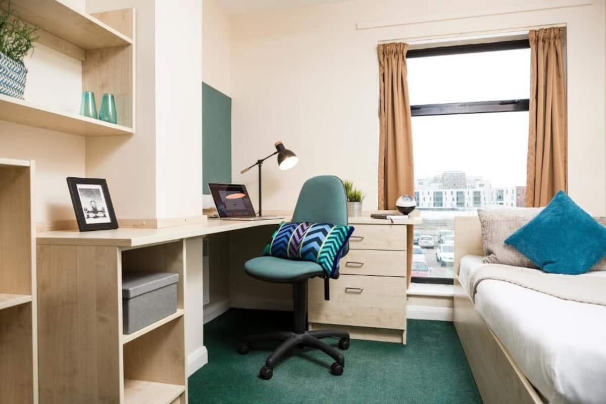 A modern bedroom with a desk, chair, and a bed.