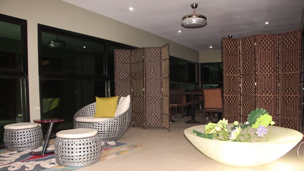 A modern lounge area with wicker furniture, a decorative plant, and a patterned partition. - ELEVEN'S Hôtel & Spa (Abidjan)