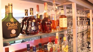 A bar area with various bottles of liquor and glasses on shelves. - ELEVEN'S Hôtel & Spa (Abidjan)