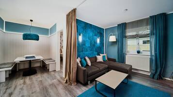 Una sala moderna con un sofá seccional, una mesita y una pared azul decorativa.