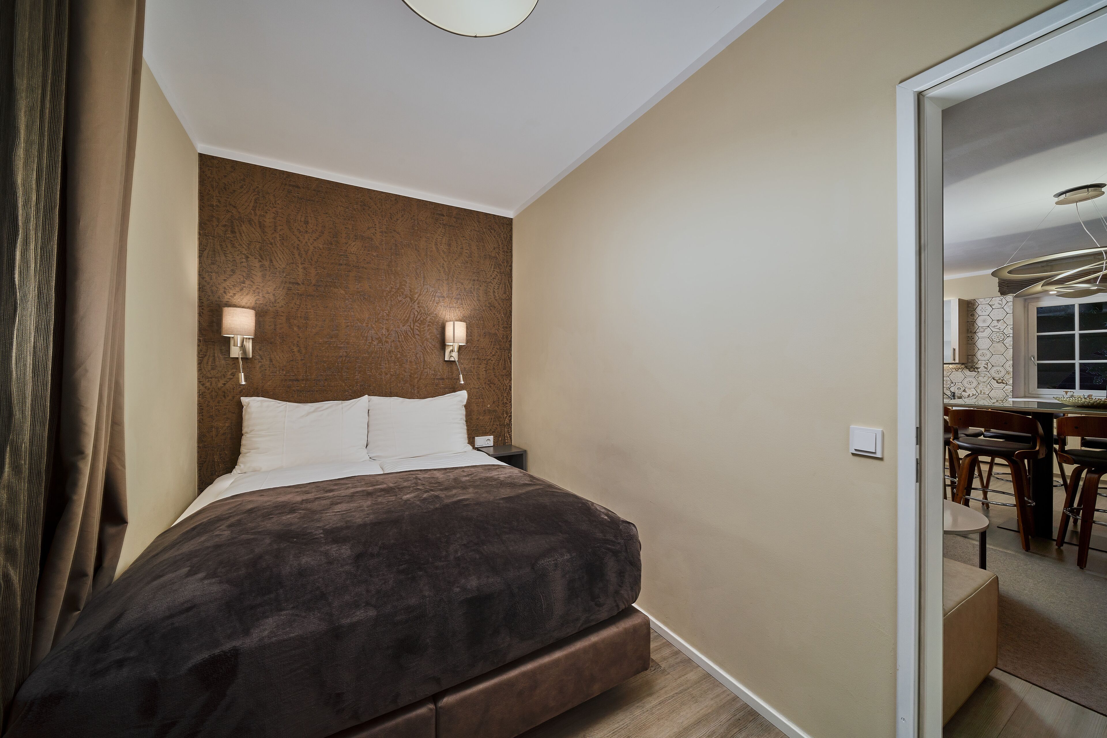 A modern bedroom with a large bed, two bedside lamps, and a wooden headboard.