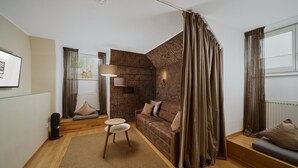 A modern living room with a brown patterned wall, a brown sofa, a small round table, and a floor lamp. - Residence Mozart (Salzburg)