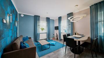 Una sala de estar moderna con un sofá, una mesa de comedor y una zona de cocina al fondo.