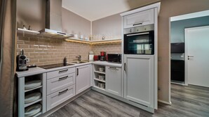 A modern kitchen with white cabinetry, a brick backsplash, and a built-in oven. - Residence Mozart (Salzburg)