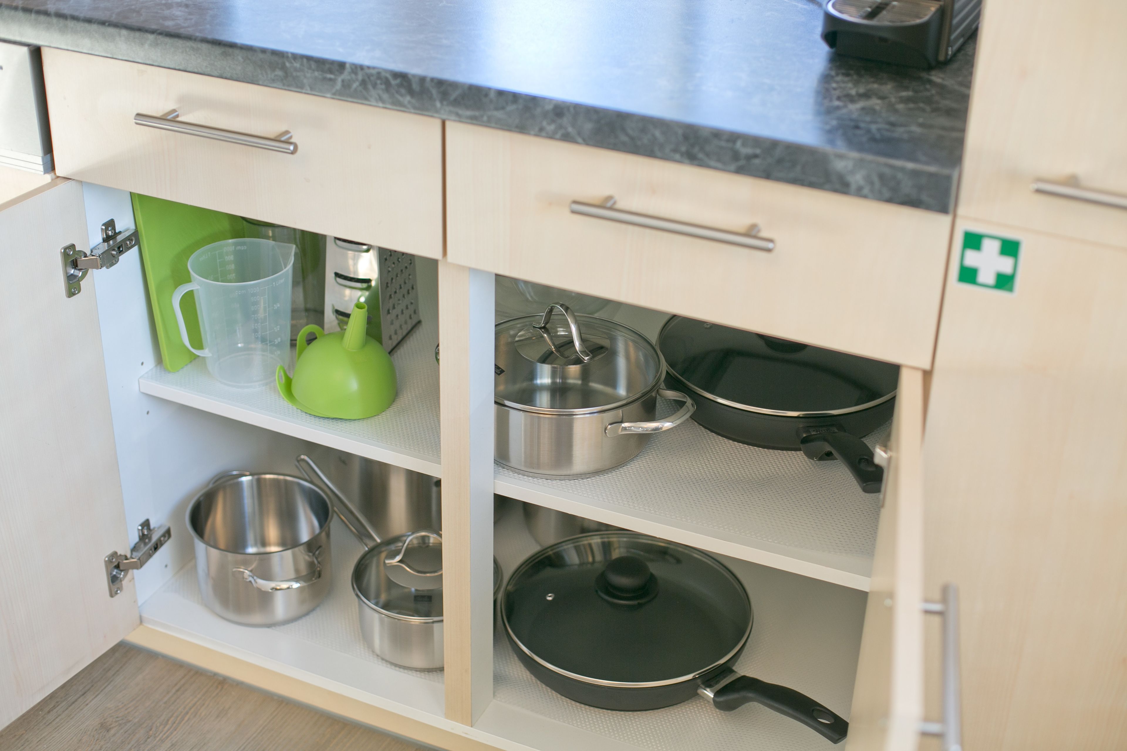 A kitchen with open cabinets displaying cookware and utensils.