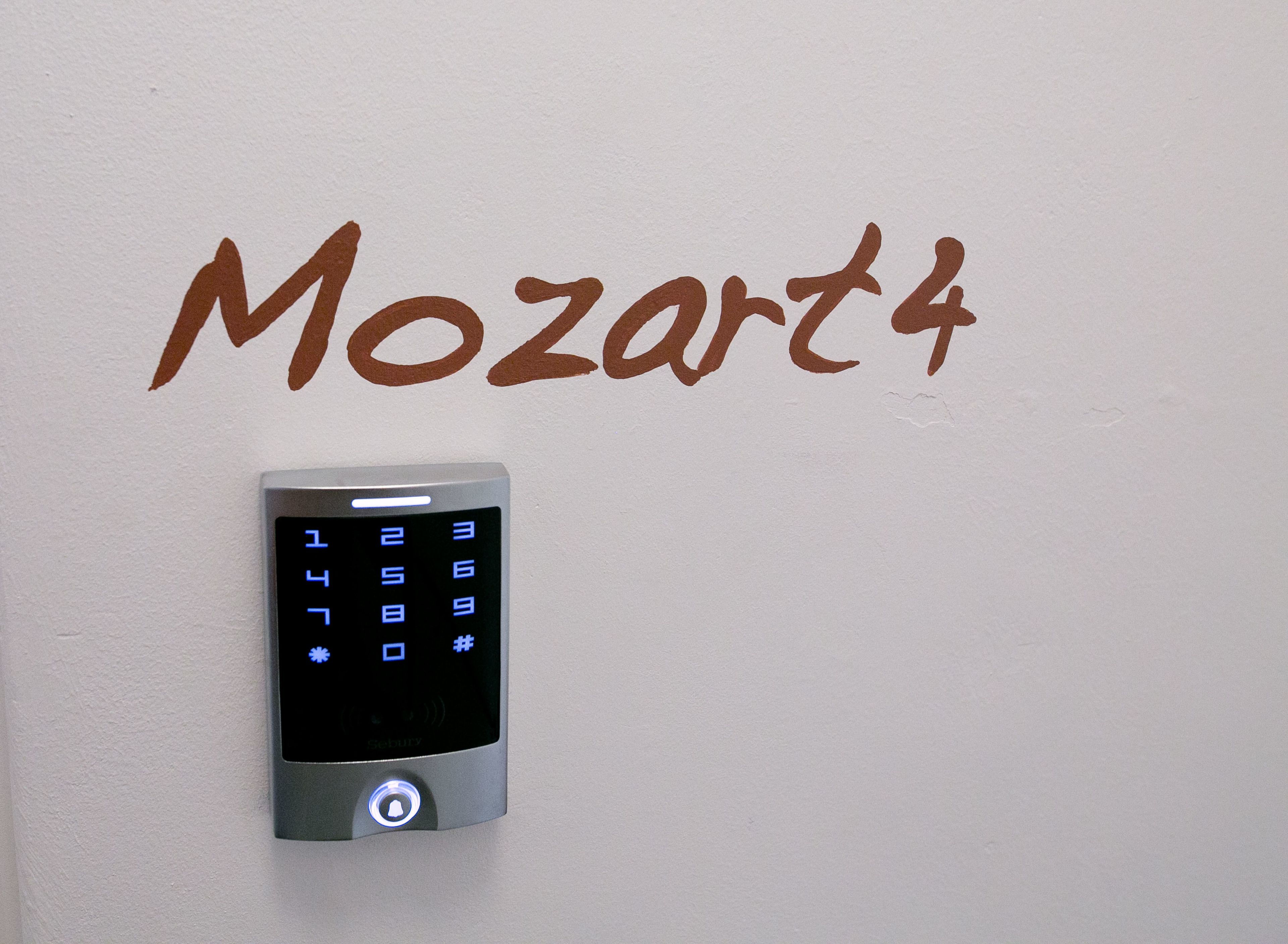 A wall-mounted security keypad with the word "Mozart" written above it.