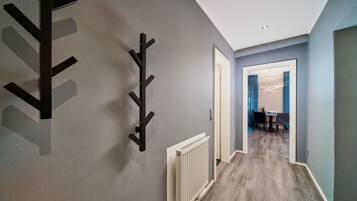 A hallway with a modern design, featuring a radiator and a black coat rack.