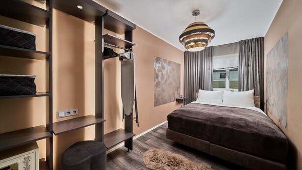 A modern bedroom with a large bed, built-in shelving, a wardrobe, and a view of the outside. - Residence Mozart (Salzburg)
