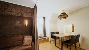 A modern living room with a brown sofa, a wooden dining table with chairs, a patterned wall, and a ceiling light fixture. - Residence Mozart (Salzburg)